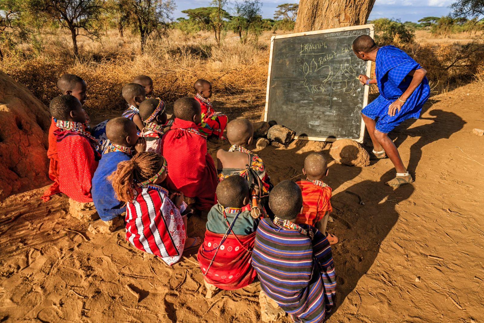 Children learning outdoors from a community teacher